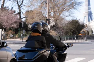 Moto taxi circulant sur Paris. deux passagers et en arrière plan la tour Eiffel