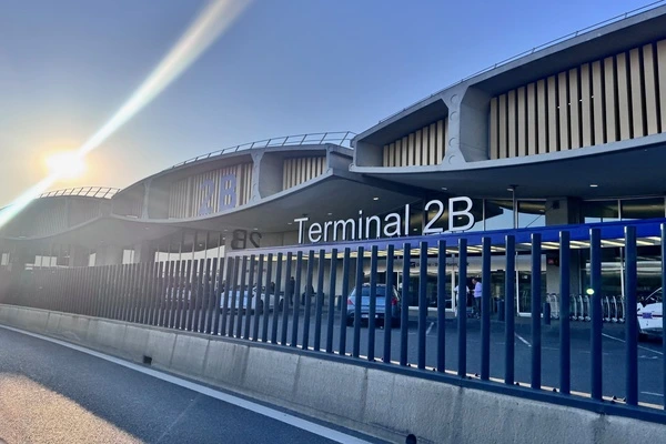 Plusieurs batiment oval, écrit dessus terminal 2B. au premier plan des barreaux