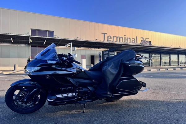 une moto au premier plan. Un aérogare à l'arriere écrit dessus terminal 2G