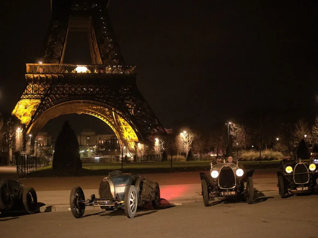 plusieurs véhicule de stationées devant la tour eiffel de nuit