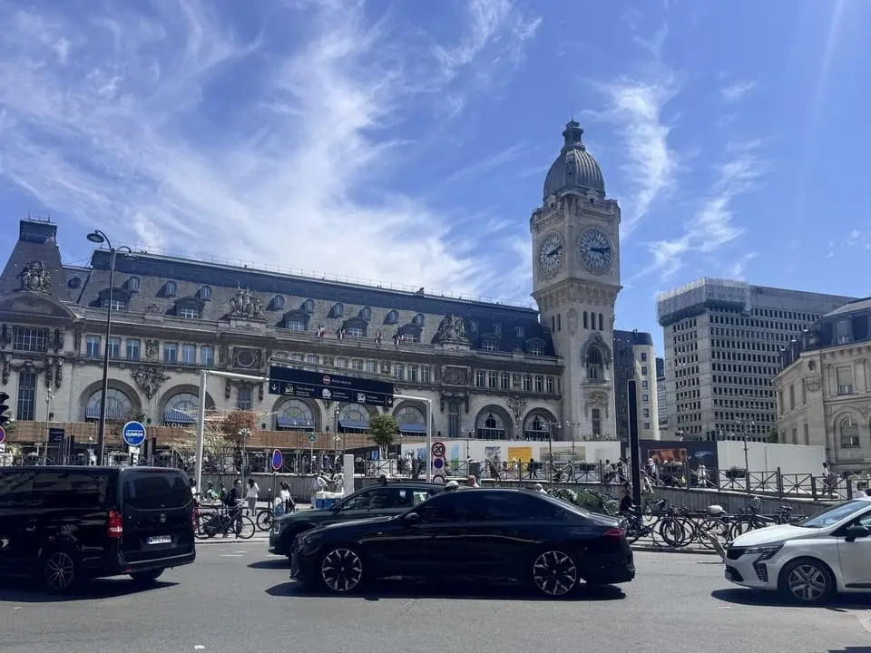 des voitures circulant en arriere plan un gare et une tour avec une horloge