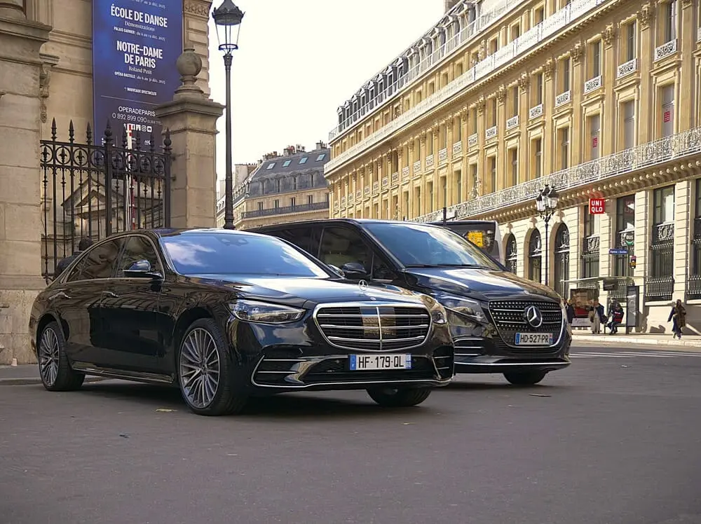 Deux voitures de couleur noire. En arrière-plan un immeuble parisiens