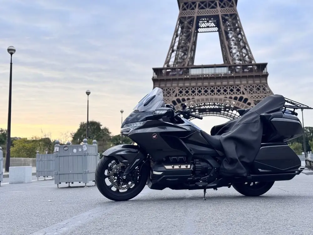 une moto au premier plan noir. A l'arriere une tour en métal la tour eiffel