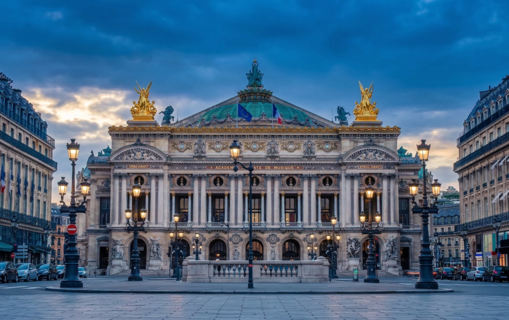 Façade illuminée de l'Opéra Garnier à Paris au crépuscule, avec ses statues dorées et son dôme vert, vue depuis une place pavée déserte